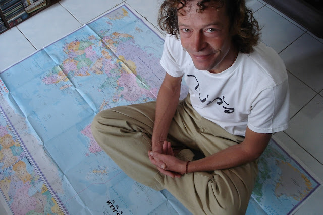 Roland'O souriant assis sur la carte du globe
