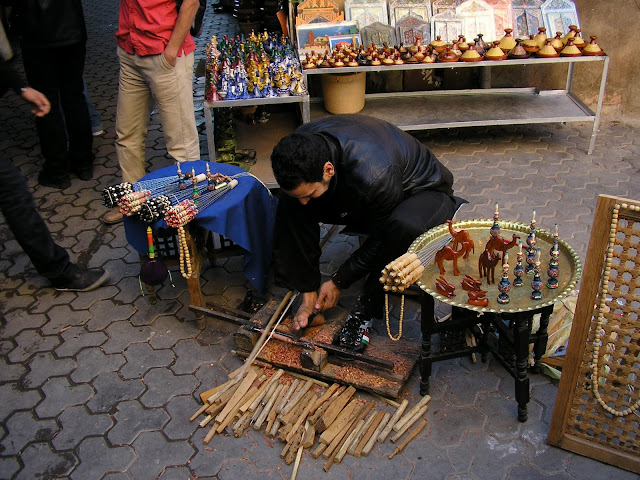 This guy uses his right hand to move the pole forward and back, making the wood object he's fashioning spin.  With his right food and left hand he guides his woodworking tool.