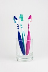 Three colored tooth-brushes in a glass