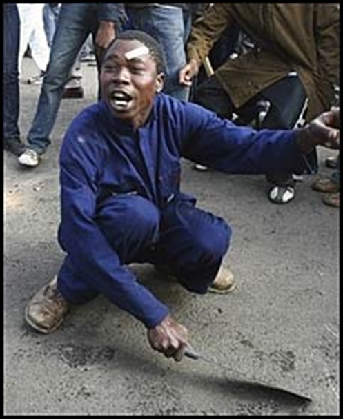 Xenophobic pogrom Rioter sharpening machete amongst crowd Reiger Park May 2008