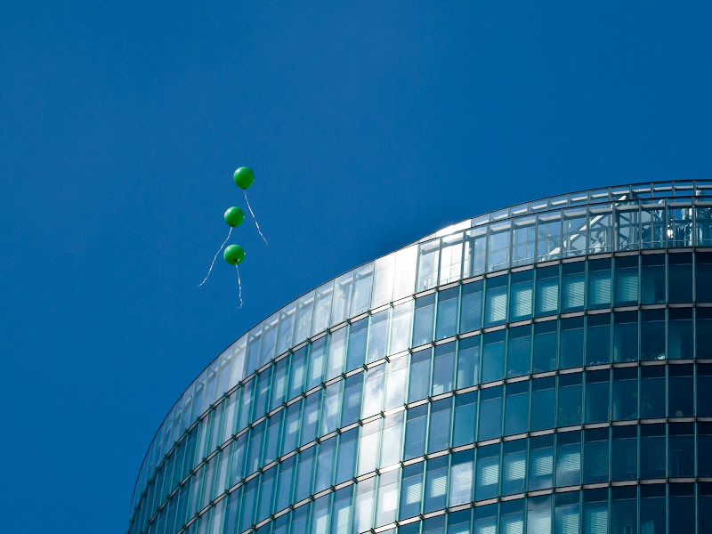 [3 GRÜNE, FLIEGENDE LUFTBALLONS VOR DER SPITZE DES BAHNTOWERS IN BERLIN AM POTSDAMER PLATZ]