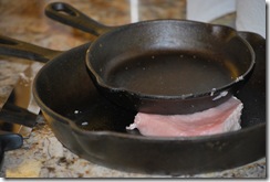 Pounding the pork flat with skillets