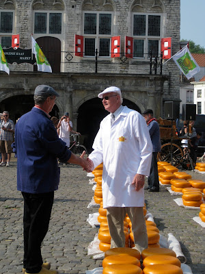 These two gentleman were bartering for the cheese; the guy in white is buying and the guy in blue is selling.  They slap hands until they come to an agreement (you probably have to see it :))