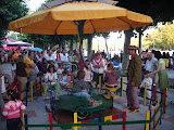 Children riding a merry-go-round while the attendant looks on.