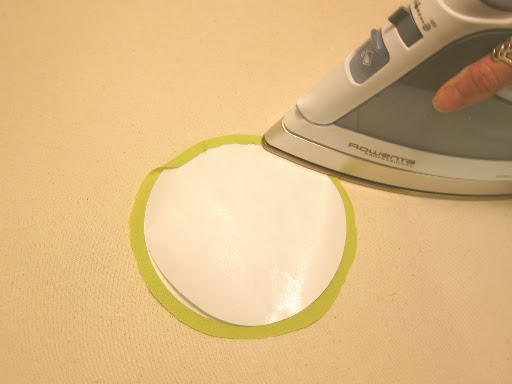 Fold the excess fabric over the two paper circles, and press in place (the fabric will stick to the top circle). If a bump shows up, simply lift the fabric and press again - freezer paper allows repositioning.