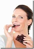 Happy pretty female eating a chocolate against white