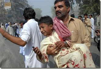 Pakistani volunteer takes away an injured boy from the site of a bomb explosion in a commercial district in Peshawar, Pakistan on Saturday, Sept. 26, 2009