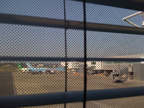 a window blinds with a plane in the background