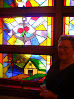 Sally Duhon and the stained glass window of "Caring for the Sick and Visiting the Prisoner" dedicated to the memory of Joseph Duhon.