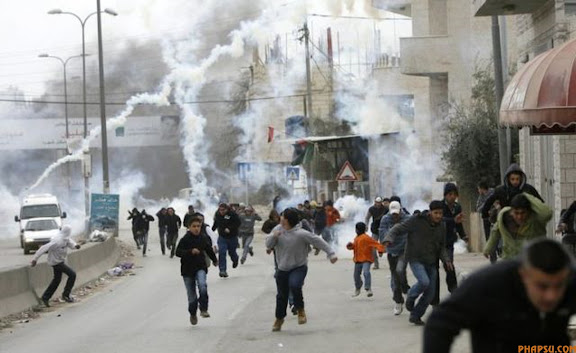RNPS IMAGES OF THE YEAR 2009 - Palestinian stone-throwers run for cover from tear gas fired by Israeli border police during scuffles at Qalandiya checkpoint near the West Bank city of Ramallah January 16, 2009. Fearing that the Gaza crisis would spark violence in the occupied West Bank and East Jerusalem, Israel imposed sweeping additional controls on movement and flooded Jerusalem's Old City with armed security personnel during Muslim weekly prayers.  REUTERS/Fadi Arouri (WEST BANK POLITICS CONFLICT MILITARY)