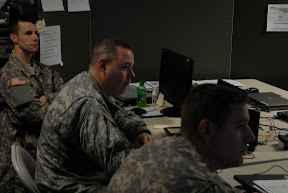 Sgt. Nate Jarett of Mankato, Minn., Maj. Rodney Rego of Rockford, Minn., and Capt. Brian Nutter of Minneapolis, Minn., view slides and listen in on the 10th Mountain Division Improvised Explosive Device Defeat Workgroup via a secure internet connection. Red Bull Photo by 34th Red Bull Infantry Public Affairs
