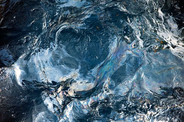 Seen up close, an iridescent sheen of oil swirls on Gulf of Mexico waters, 11 May 2010. Photograph by Gerald Herbert, AP