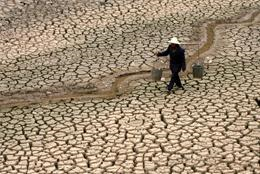 A man carries water along a dried river bed. The drought in China's Yunnan province has left millions without water. AP PHOTO