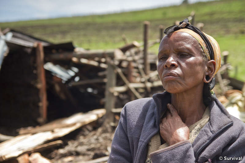 An Ogiek woman sits in front of the remains of her demolished house. © Survival