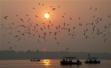 People travel in boats as the sun sets for the last time in 2008 over the banks of river Ganges in the northern Indian city of Allahabad December 31, 2008. REUTERS/Jitendra Prakash