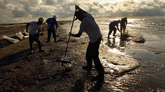 Workers hired by BP rake up globs of oil that have come ashore on the beaches near Port Fourchon and Grand Isle in southern Louisiana. (Carolyn Cole / Los Angeles Times / May 22, 2010)
