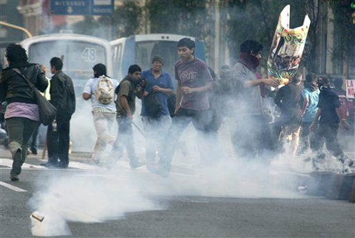 Demonstrators run from tear gas fired by police officers, unseen, during a protest in favor of Amazon Indians in Lima, Thursday, June 11, 2009. Peru's Congress indefinitely suspended on Wednesday two key legislative decrees that spurred the Amazon Indian protests that erupted in bloodshed during a government crackdown last week. (AP Photo / Karel Navarro)
