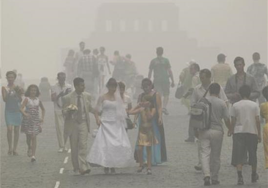 A newly married couple walks along Red Square amidst heavy smog, caused by peat fires in nearby forests, with the mausoleum of Soviet state founder Vladimir Lenin in the background, in central Moscow August 7, 2010. Dense clouds of acrid smoke from peat and forest fires choked Russia's capital on Friday, seeping into homes and offices, diverting planes and prompting exhausted Muscovites to wear surgical masks to filter the foul air. REUTERS / Sergei Karpukhin