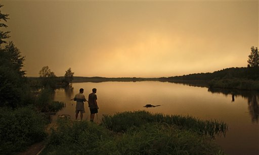 Local residents look at a heavy smog from a peat fire in a forest near the town of Shatura, some 130 km (81 miles) southeast of Moscow, Thursday, July 29, 2010. Peat swamps started burning in central Russia following an unprecedented heat wave. AP Photo / Sergey Ponomarev