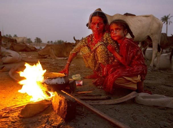 A Pakistani mother and her daughter make some tea over a fire, living on the street over two weeks after the floods forced them to flee August 13, 2010 in Sukkur, Pakistan. The country's agricultural heartland has been devastated as rice, corn and wheat fields are flooded creating a massive lake that goes on for many miles. PAULA BRONSTEIN / GETTY IMAGES