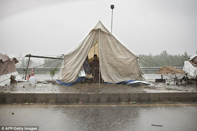 A Pakistani boy shelters from heavy rain inside a tent erected beside a motorway in the outskirts of Peshawar. AFP / Getty Images