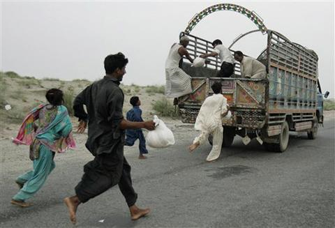Pakistanis run to get relief supplies thrown from a passing truck near a camp for people displaced by floods in Muzafffargarh district, Punjab province, 8 September 2010. AP