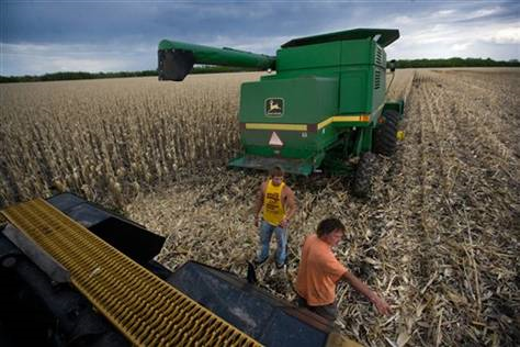 In this June 1, 2009, file photo Jeff Trosen, right, and his son, Broc, working to free a stuck combine in a corn field north of Arvilla, ND. Warmer and wetter weather in large swaths of the country have helped farmers grow crops in some regions that only a few decades ago were too dry or cold. AP Photo / The Grand Forks Herald / Eric Hylden / File