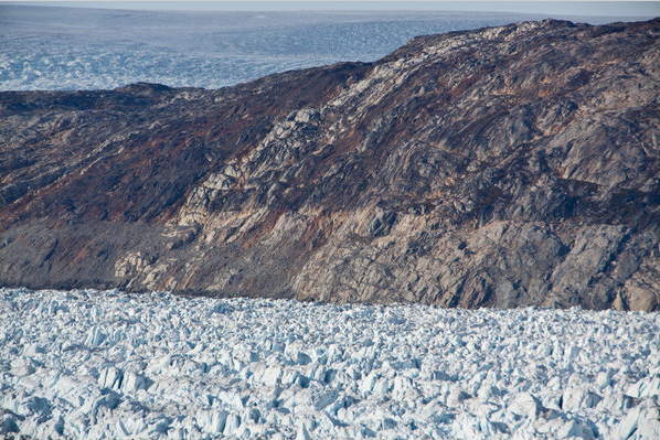 This photo shows the 'bathtub ring' above Helheim Glacier. It was created in the middle of the last decade when the glacier sped up and thinned, exposing rock that had once been covered by ice. The light-colored band of rock is about 300 feet thick. The Greenland ice sheet can be seen in the background at the top of the picture. Credit: Tony Cenicola / The New York Times