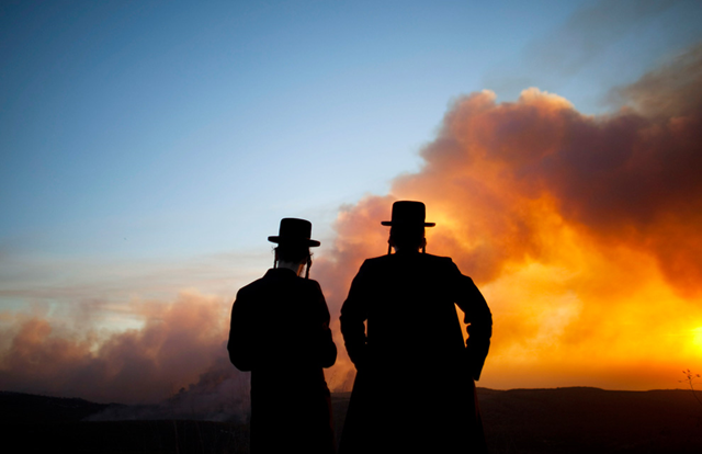 Ultra orthodox Jewish men watch as smoke from a wildfire rises into the sky on December 2, 2010 in Haifa, Israel. A large forest fire in northern Israel has reportedly killed at least 42 people. Uriel Sinai / Getty Images
