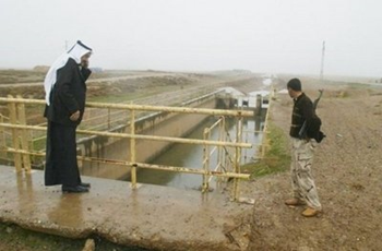 An armed Sahwa militiaman stands next to an Iraqi Arab farmer checking low water levels in a canal running through arid agricultural land in the Hawijah district of Kirkuk in northern Iraq on Saturday. A worsening water shortage in Iraq is raising tensions in the multi-ethnic Kirkuk province, where Arab farmers accuse the Kurdistan region of ruining them by closing the valves to a dam in winter. AFP / File / Marwan Ibrahim