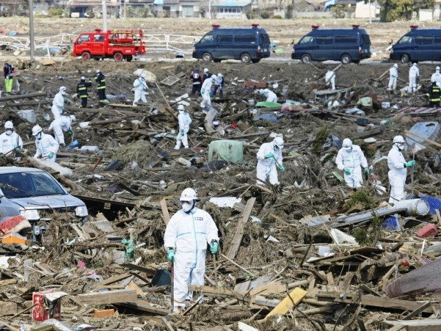 Police officers wearing protective suits search for victims of an earthquake and a tsunami in Fukushima Prefecture in Minamisoma City in this photo taken by Yomiuri Shimbun on March 28, 2011. REUTERS