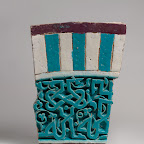 his carved tile was originally set into the facade of a building in present-day Uzbekistan. The central panel consists of a deeply carved Arabic inscription in plaited kufic script against a background of vegetal scrolls covered in a luminous transparent turquoise glaze. The inscription, which reads "[al-mulk] li-llah al-mu[lk li-llah]" (Sovereignty is for God. Sovereignty is for God), is framed by two narrow light blue borders and is crowned by a wide panel with seven vertical bands in alternating turquoise and white with a horizontal border in dark manganese at the top.