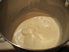 Whipping the warm egg mixture until it is the texture of soft whipped cream.