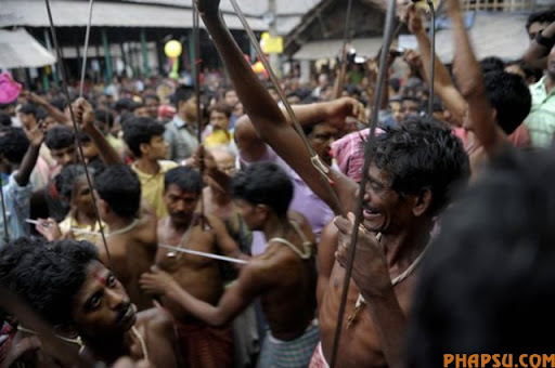 Indian Hindu devotees celebrate with metal rods before piercing their tongues during the ritual of Shiva Gajan at a village in Bainan, some 80 kms south of Kolkata, on April 14, 2010. Devotees believe that by enduring the pain, Shiva, the Hindu god of destruction, will grant their prayers. Thousands took part in the month-long festival which culminates with the worship of Shiva on the auspicious day of Chaitra Sankranti, the last day of the Bengali calendar year.    AFP PHOTO/Deshakalyan CHOWDHURY (Photo credit should read DESHAKALYAN CHOWDHURY/AFP/Getty Images)