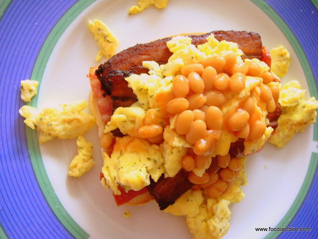 Scrambled egg on hard dough bread with plaintain, bacon and beans