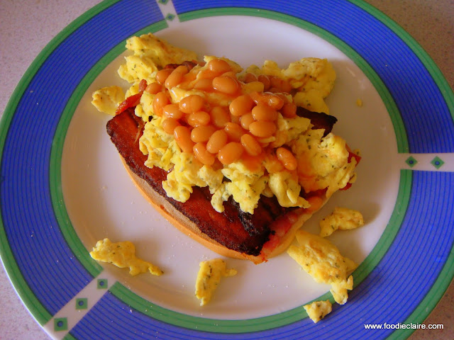 Scrambled egg on hard dough bread with plaintain, bacon and beans