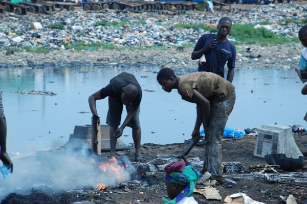 Alcuni ragazzi stannno bruciando pezzi di dispositivi elettronici nella discarica di Agbogbloshie, in Ghana