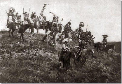 Oglala war party. Several Oglala men, many wearing war bonnets, on horseback riding down hill. Photo by Edward S. Curtis, 1907.