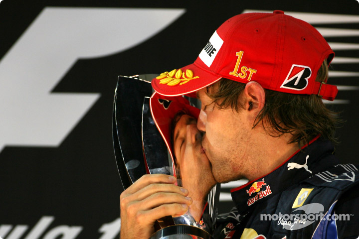 Себастьян Феттель целует трофей на подиуме Гран-при Абу-Даби 2010
