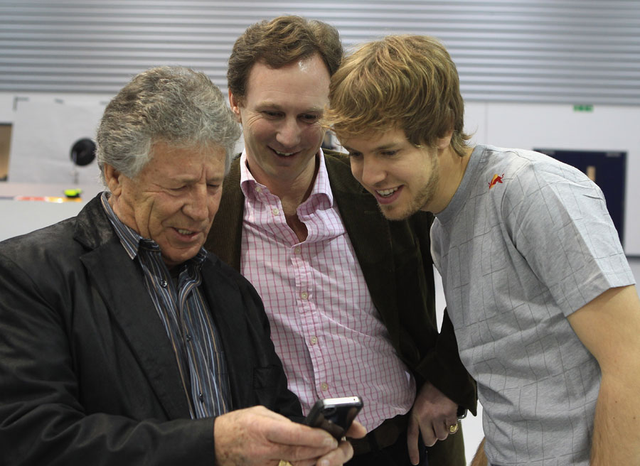 Марио Андретти показывает Себастьяну Феттелю и Кристиану Хорнеру что-то на телефоне