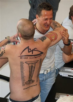 Михаэль Шумахер обнимается с болельщиком с татуировкой со всеми победами 7ми кратного чемпиона на автограф-сессии перед Гран-при Малайзии 2011