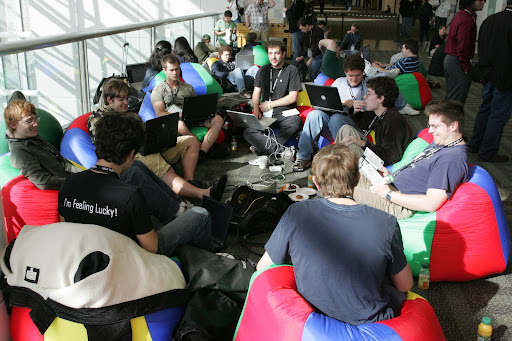 The crew hanging out on beanbags with laptops and some random dude