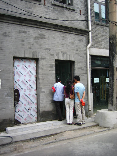 A crowd gathers to watch the torch relay from a back alley parallel to Qianmen Dajie, the main torch's main course.