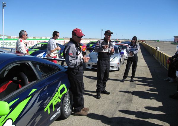 Phil Reed (left) and Bryn MacKinnon (right, sporting the always-sexy head sock) listen to instructor Matt Whatisname at the Big Track