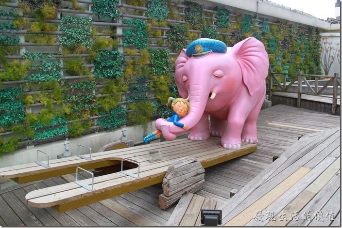 花蓮-翰品酒店。游泳池旁有一隻踩在蹺蹺板上面的大象正與小女孩擁抱在一起，他們正等著和遊客們比賽重量。