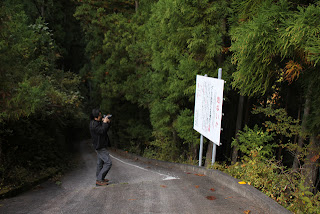 横沢川第2ダムへの通路入口にある放流注意看板を撮影する宮島さん