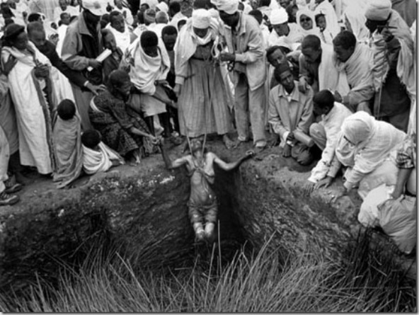 Women that have been unable to have children take bath in the holy water during a long time in a ritual for fertility meanwhile a priest pray at the side of pool outside of Bet Maryam church. This immersion in cold water produces a shock in this woman.