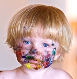 Young boy with face covered in colourful paint