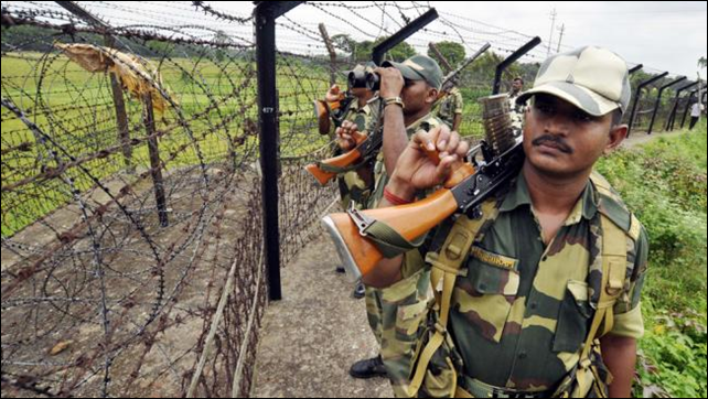 Indian Border Security Force personnel peer through the barb wire fence that separates India and Bangladesh during a security patrol in June 2013. By late 2013, about 1,700 of the fence's planned 2,116 miles had been built. When complete, nearly all of Bangladesh will be encircled by a militarized border. Photo: STRDEL / AFP  Getty Images
