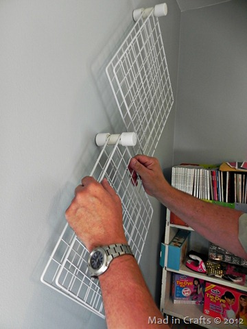 man's hands placing the paint storage racks on the wall